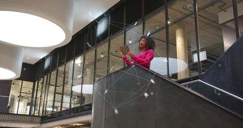 Businesswoman Uses Tablet in Futuristic Corporate Atrium