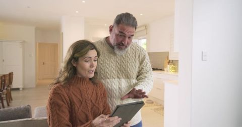 Couple collaborating on tablet in modern living room