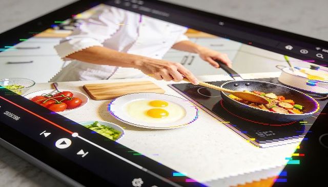Glitchy tablet cooking tutorial showing chef hands stirring vegetables on induction hob