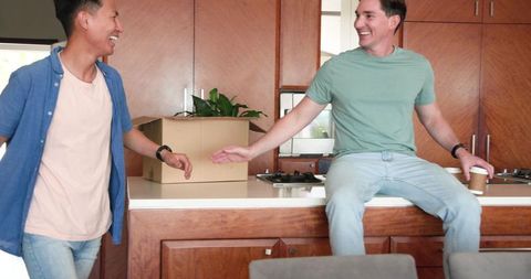 Male Couple Sharing Happy Moment Unpacking in New Home Kitchen