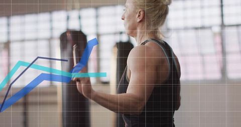 Female athlete practicing boxing on heavy bag with performance graph overlay