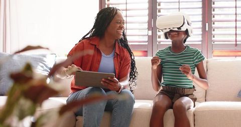 African American mother and child sharing virtual reality experience on couch with tablet
