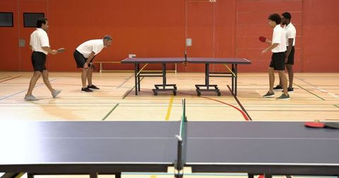 Diverse Friends Playing Doubles Table Tennis in Gym