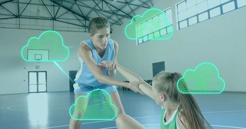 Female basketball players helping teammate up with cloud technology overlays on indoor court