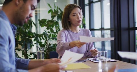 Professional Employees Collaborating in Glass-Walled Office