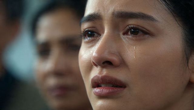 Closeup asian woman crying with tear streaks conveying grief and resilience in crowd