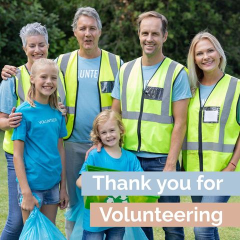 Diverse group of smiling volunteers wearing vests outdoors