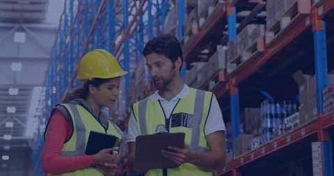 Warehouse workers checking inventory on tablet, wearing hi-vis vests and yellow hard hat