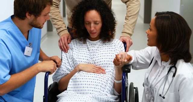 A diverse group of healthcare professionals, including a Caucasian nurse and an Asian doctor, are attending to a middle-aged patient in a wheelchair, with copy space. They appear to be in a hospital setting, providing care and support to the patient.
