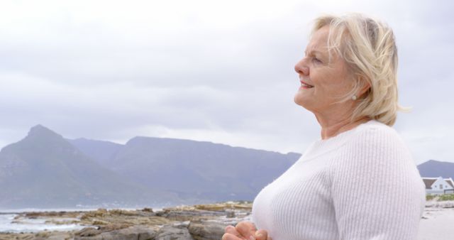 Elderly Woman Enjoying Peaceful Beach View and Mountains - Download Free Stock Images Pikwizard.com