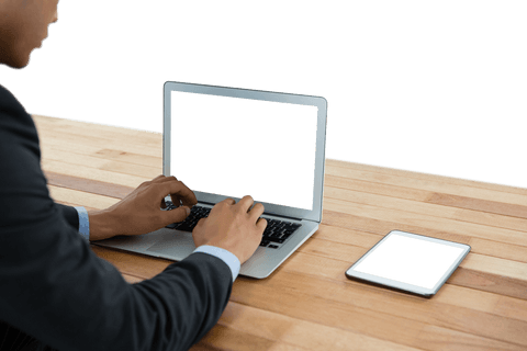 Transparent focused businessman typing on laptop with tablet on wooden table - Download Free Stock Videos Pikwizard.com
