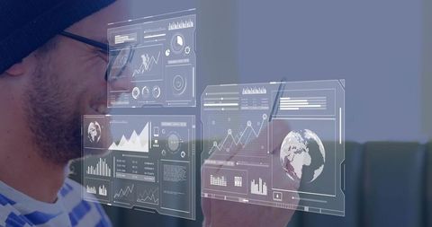 Man in beanie and glasses interacting with holographic data dashboards