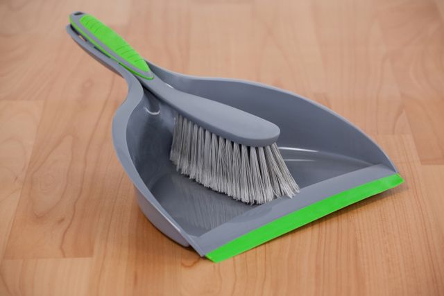 Close-up of dustpan and sweeping brush on wooden floor