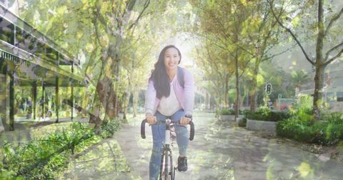 Asian Woman Cycling Through Scenic Path in Sunny Park - Download Free Stock Images Pikwizard.com