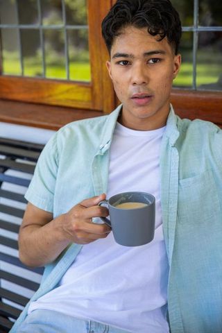 Young Man Enjoying Coffee on Porch with View of Garden