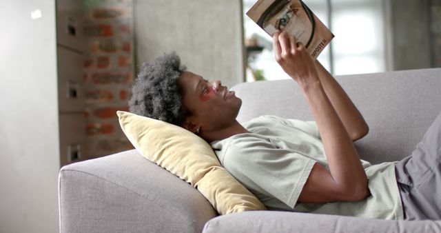 Young Man Relaxing on Sofa Reading a Book - Download Free Stock Images Pikwizard.com