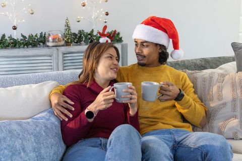 Couple enjoying cozy christmas morning on sofa with santa hat and reindeer antlers