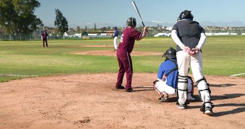 High school baseball game with batter and catcher on field