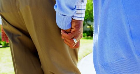 Elderly couple holding hands in tranquil garden walk