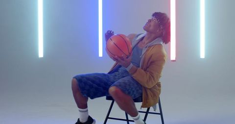 Athlete Holding Basketball in Neon Lit Studio