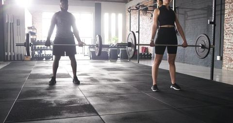 Focused Training Partners Lifting Barbells in Urban Gym Setting
