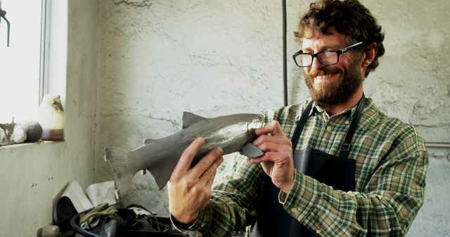 Man Smiling Holding Metal Fish Sculpture in Workshop - Download Free Stock Images Pikwizard.com