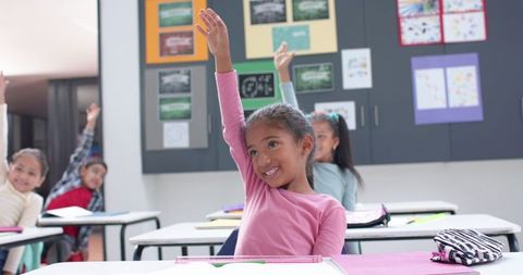 Enthusiastic students raising hands in classroom during lesson
