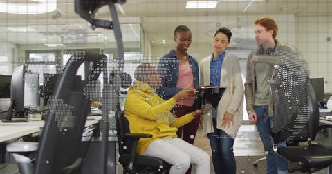 Diverse team collaborating around tablet in modern open office with world map overlay