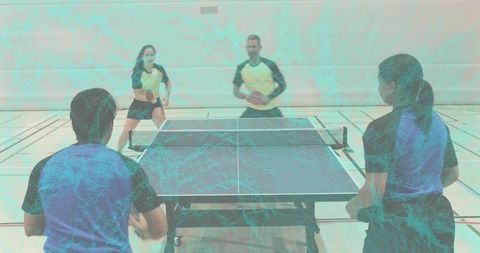 Competitive table tennis doubles playing intense rally in indoor sports hall teamwork