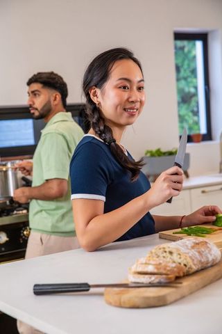 Multitasking couple preparing fresh meal in modern kitchen
