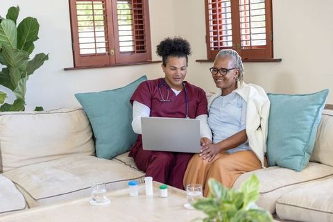 Homecare nurse reviewing meds with african american senior on laptop for telemedicine care
