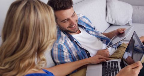 Happy Couple Using Tablets and Laptop on Cozy Sofa
