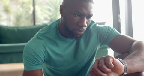 Man Relaxing Indoors Checking Smartwatch for Fitness Tracking