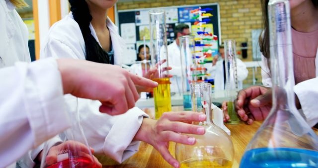 Students in a science lab are engaged in an experiment, with colorful liquids in beakers and flasks, with copy space. Their focus and the vibrant chemicals suggest a hands-on learning experience in chemistry.