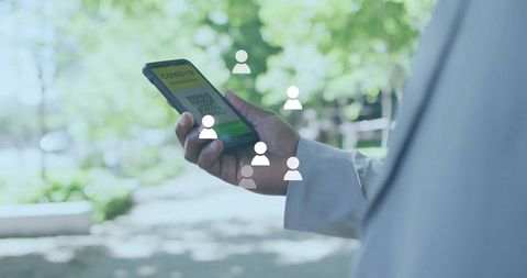 Man in coat checking covid-19 qr code in sunny garden