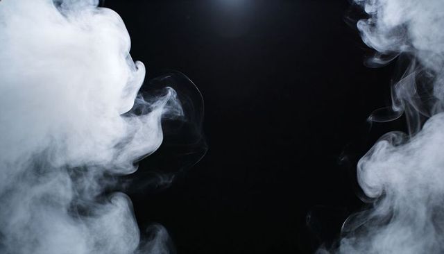 Swirling white smoke plumes framing black background with dramatic rim lighting