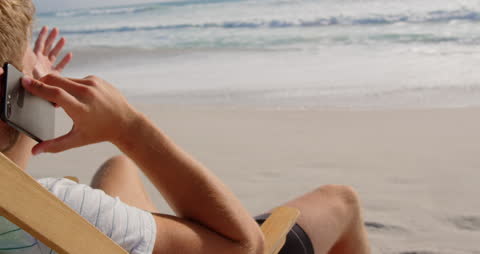 Man Relaxing on Beach Lounger Talking on Mobile Phone