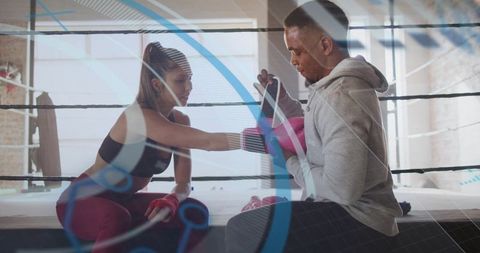 Female boxer practicing jab with coach holding focus mitts in boxing ring training