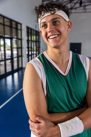 Smiling Teen Male Basketball Player in Green Jersey Boosting Team Spirit