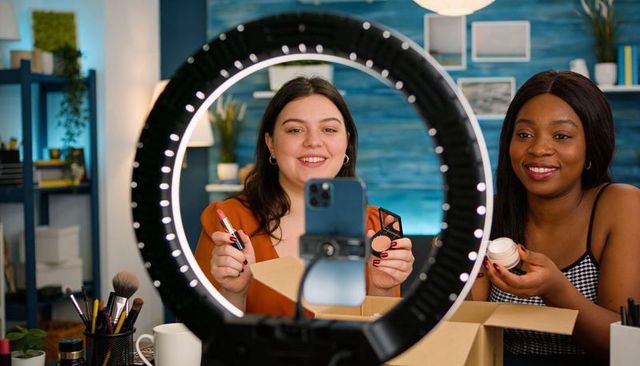 Influencers unboxing makeup and recording beauty tutorial with ring light and smartphone