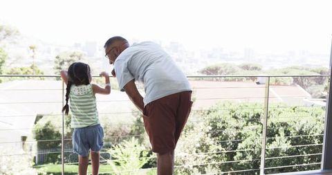 Grandfather Sharing a View with Granddaughter on Balcony Cityscape