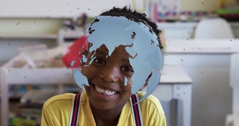 Smiling student sitting at desk wearing yellow top and striped suspenders with globe overlay