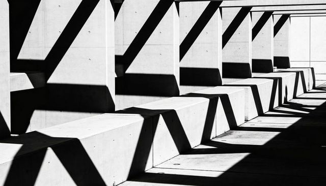 Monochrome Concrete Benches Casting Zigzag Shadows in Minimalist Colonnade, Architectural Geometry