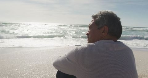 Senior Man Reflecting Peacefully on Serene Beach at Sunset