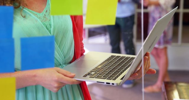 Woman working on laptop with sticky notes in foreground - Download Free Stock Images Pikwizard.com