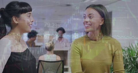 Business Women Collaborating Amid Economic Graphs Overlay