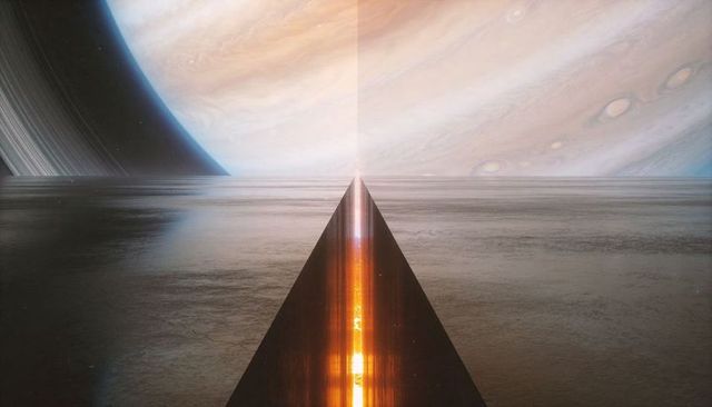 Rising triangular prism casting glowing orange seam on alien shoreline under ringed planet