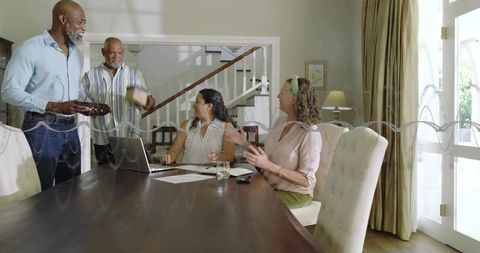 Multigenerational family gathering at dining table discussing finances with laptop