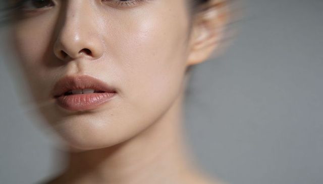 Asian woman closeup showing lips and skin texture, minimalist serene headshot for beauty