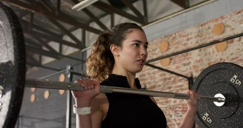 Focused Woman Lifting Barbell in Industrial Style Gym